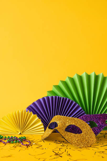 istock Side vertical view Colorful items for a Mardi Gras celebration include a glittery mask, paper fans, and beads 2193847948