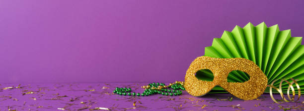 istock Colorful side view Mardi Gras decorations featuring a mask, beads, and confetti on a vibrant purple surface, perfect for evoking excitement, celebration, and festive spirit 2193847960