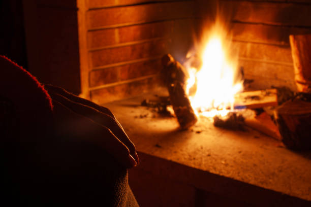 Woman relaxing by the fireplace on a cold winter evening, enjoying the warmth and cozy atmosphere