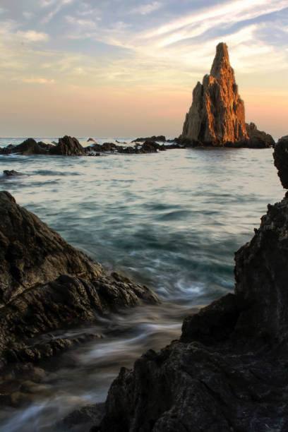 istock Eroded rock formation emerging from the ocean at sunset 2193849822