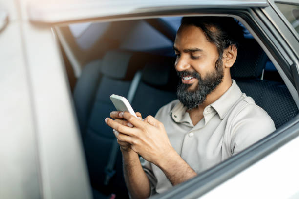 istock Smiling middle eastern man engages with his smartphone while relaxed in a car during the afternoon in a bustling urban setting 2193852797