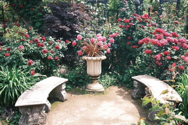 A serene garden scene featuring a stone archway surrounded by colorful flowers and greenery, with a paved pathway leading through the landscape