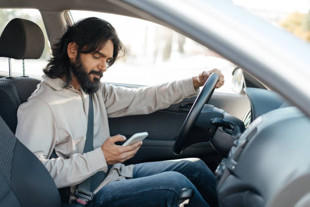 istock Middle eastern Man using smartphone while seated in a car during daylight commute in an urban area 2193853336