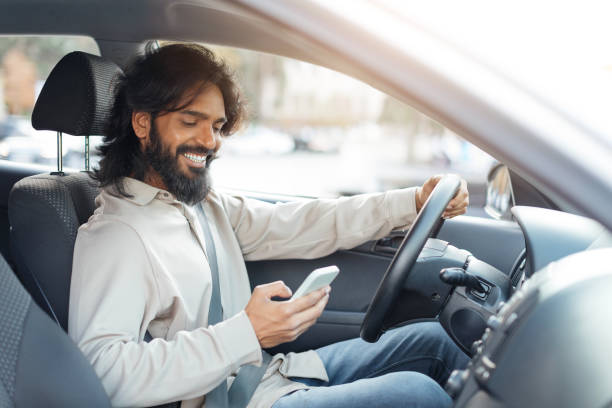 istock Man driving a car while checking his smartphone in an urban area during daylight hours 2193853978