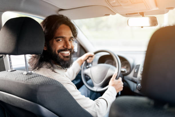 istock Smiling man driving a car on a sunny day with trees in the background 2193856092