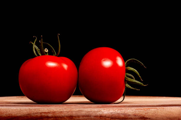 Tomatoes on a wooden board against a black background