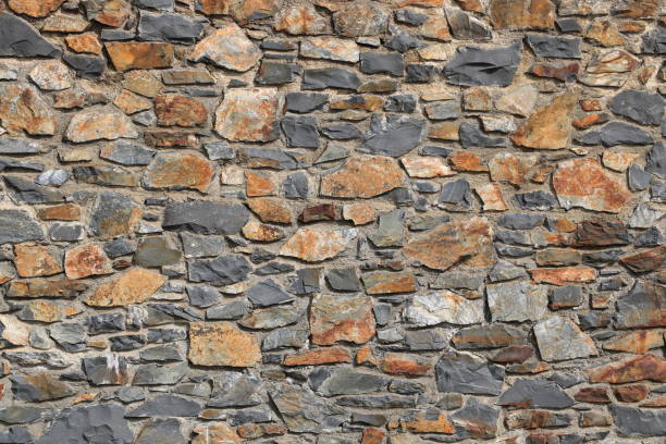 A wall made of stone with a rough texture. The wall is made of many different sized stones and has a natural, earthy feel to it