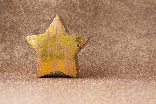 Golden star displayed on a textured brown glittery background, evoking celebration and festive atmosphere. Ideal for seasonal, decorative, or celebratory themes, emphasizing elegance, warmth, and charm.