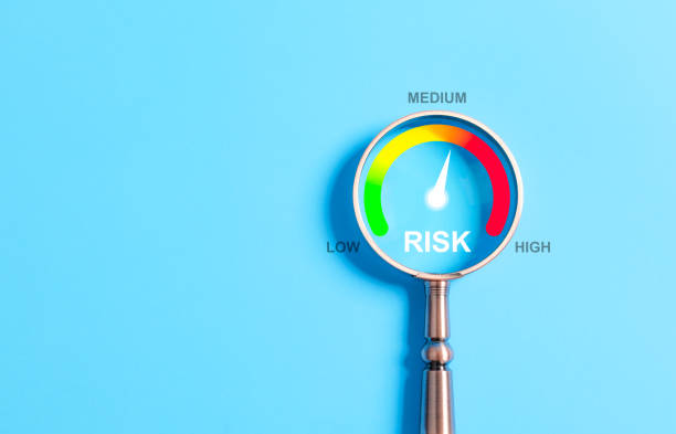 istock Business Risk Assessment and Management Concept. A magnifying glass highlighting a risk level gauge on a blue background, indicating low, medium, and high risk for business assessment purposes. 2193865946