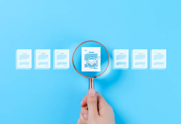 istock Document Review and Quality Control Process Concept. A hand holding a magnifying glass focuses on a document with a checkmark, document review, and approval processes. Certificate management, Audit, 2193865978