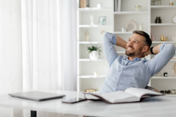 istock A relaxed man enjoys his time at a cozy workspace surrounded by natural light while reading a book in the afternoon 2193866375