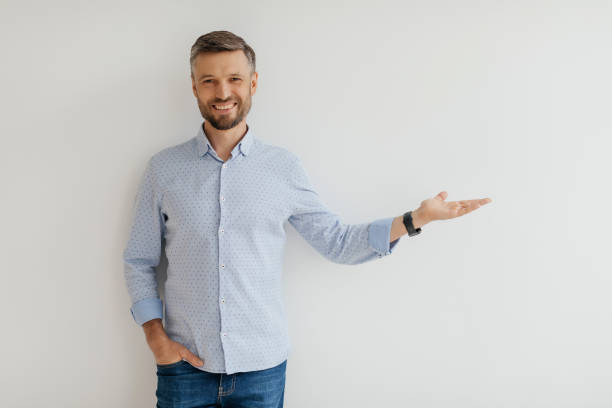 istock Cheerful man presenting with a friendly smile against a plain white background in a modern indoor setting 2193871005