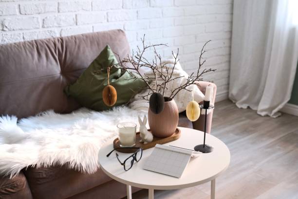istock A beautifully cozy living room with modern easter home decor that includes vase with dry branches and eggs, notebook, glasses, ceramic rabbit, candles on coffee table. 2193871731