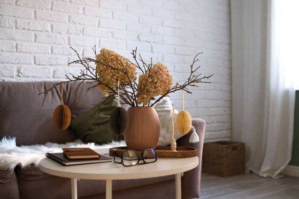 istock A beautifully cozy living room with modern easter home decor that includes vase with dry branches, flowers and eggs, notebook, glasses, candles on coffee table. 2193873163