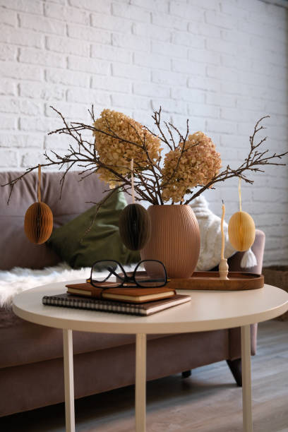 istock A beautifully cozy living room with modern easter home decor that includes vase with dry branches, flowers and eggs, notebook, glasses, candles on coffee table. 2193873187