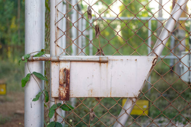 Closed locking wire fence door with rustic handle at the abandoned place. Building object close-up photo.