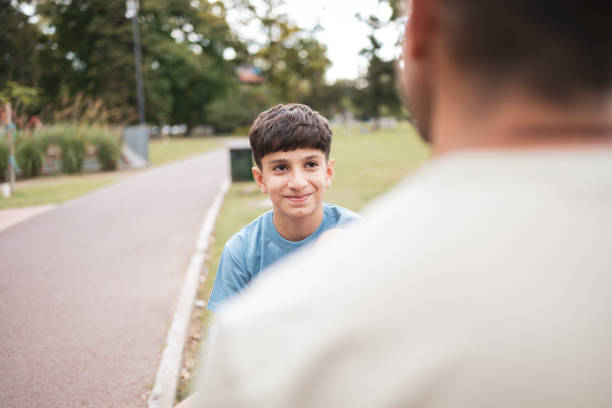 A young father and his son enjoy a day at the park, bonding and sharing memorable moments in a serene outdoor setting.