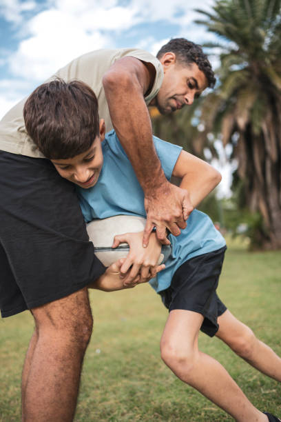 istock Father and son bond while playing rugby outdoors in a sunny park 2193873945