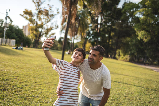 istock Father and son enjoying quality time together at a sunlit park.Taking a selfie 2193873990