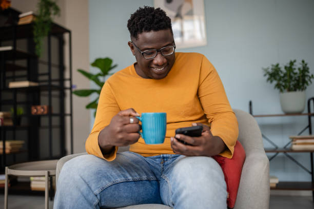 istock Relaxed individual sipping from mug while on smartphone 2193878352