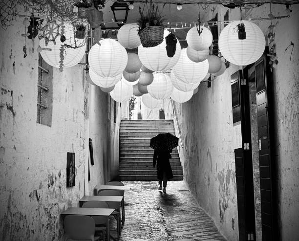 A person walks underneath decorative lights in Polignano a Mare, Puglia.