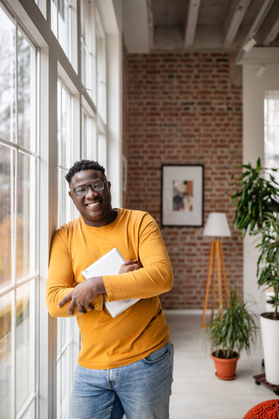 istock Joyful man through window, holding tablet indoors 2193879944