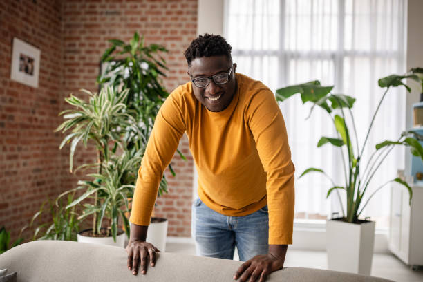 istock Joyful man leaning on sofa in plant-decorated room. 2193880692