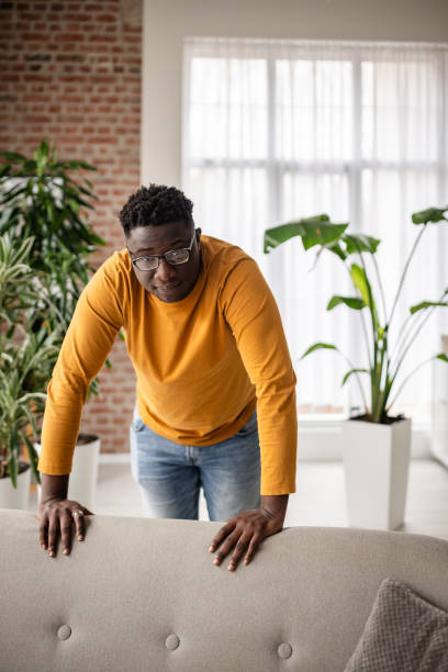 istock Cheerful man in yellow sweater leans over a sofa. 2193880777