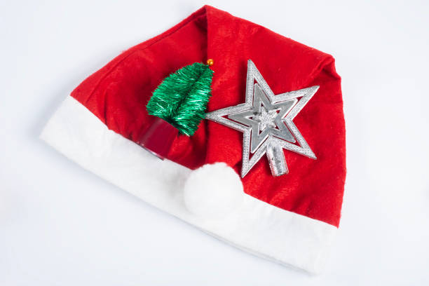 Top view of Red Santa hat with silver star and green Christmas tree on white background. Perfect for Christmas celebrations, holiday designs, seasonal greetings, and festive decorations.