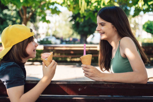 istock Two kids laughing with ice cream cones in a park. 2193885347