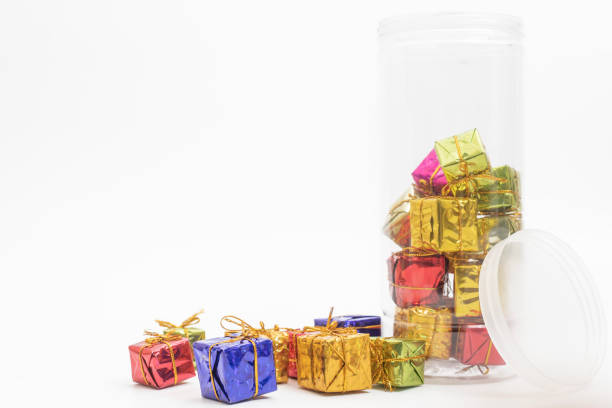 Colorful miniature gift boxes placed inside a clear plastic jar, lying on its side against a white background. perfect for holiday gift decor.