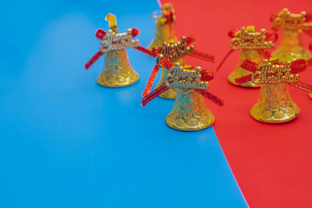 A festive holiday composition featuring golden Christmas bells adorned with vibrant red bows, set against a striking split blue and red background.