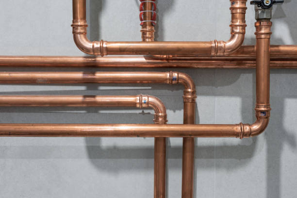 Cooper pipes connected with pressed or crimped fittings create an industrial pattern on grey tiled wall background