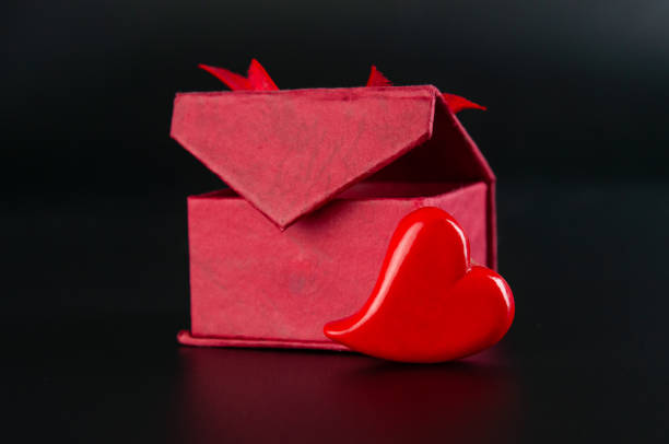 Red gift box and heart on black background. Valentines day card