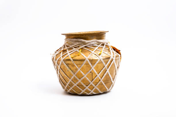 A golden brass pot wrapped with a decorative rope, traditionally used in Indian puja ceremonies, placed against a clean white background. Ideal for cultural and spiritual themes.