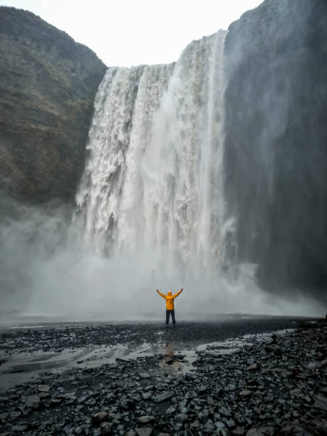 istock Person in yellow jacket standing before majestic Skogafoss Waterfall calling Floki Waterfall in Golden Circle in Iceland 2193889279