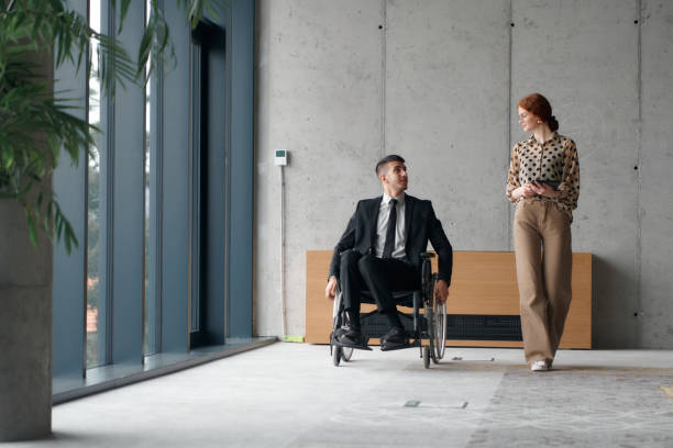 istock Director in a Wheelchair Navigating the Office While Discussing Business Challenges with a Colleague 2193891655