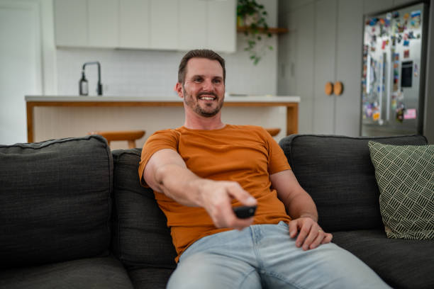 istock Man with remote control sitting comfortably on sofa. 2193893192