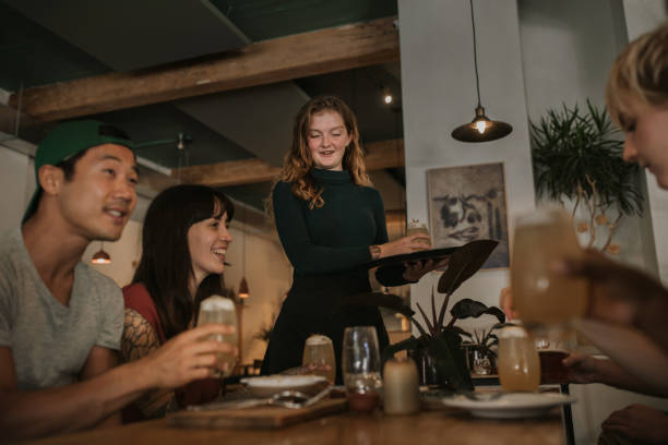 istock Smiling watiress bringing customers drinks in a bar 2193894168
