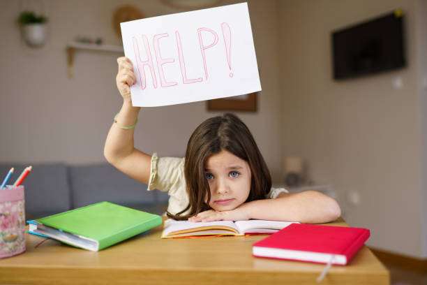istock A girl with a HELP sign is doing her homework 2193894593