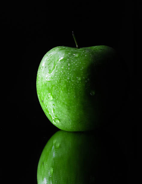 Wet droplets on green granny smith apple with black background. High quality photo