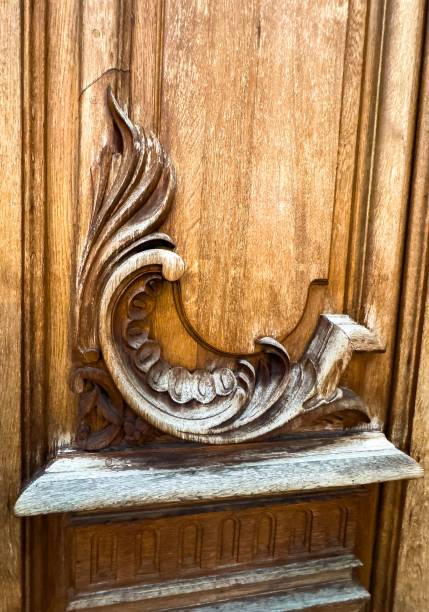 Close-up of an elegant wooden door featuring intricate carved details, including swirling decorative patterns and symmetrical geometric designs. A beautiful example of traditional craftsmanship