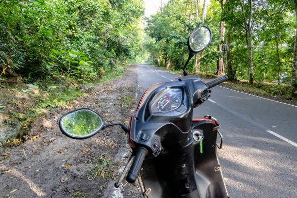 istock scooty two wheeler journey on empty forest road with lush green 2193901880