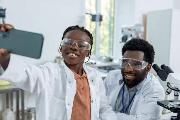 istock Happy teacher and student in lab coats making selfie on a phone 2193901971