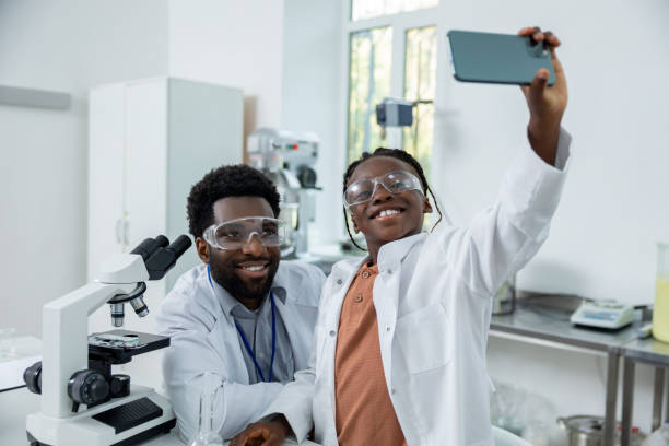 istock Happy teacher and student in lab coats making selfie on a phone 2193901973