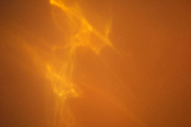 Abstract blurred yellow background, backdrop with sun reflection. Caustic effect of sunlight. Empty space for design with solar glare