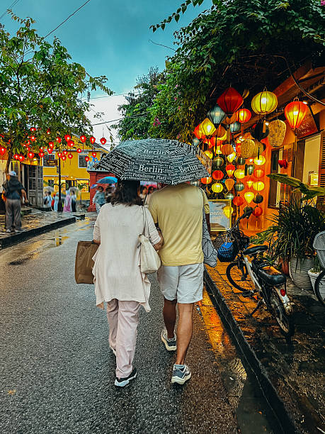istock Couple Strolling Under Umbrellas Through Lantern-Lit Street 2193909661