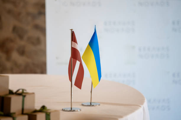 istock Latvia and Ukraine Table Flags in Formal Setting with Gifts 2193910439