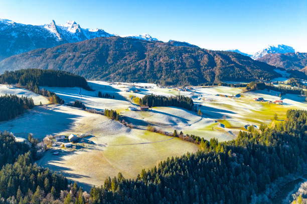 Aerial view of Alpine landscape. Contrast of mountains covered with snow and mountains covered with autumn forest. Autumn and winter. Salzkammergut, Austria