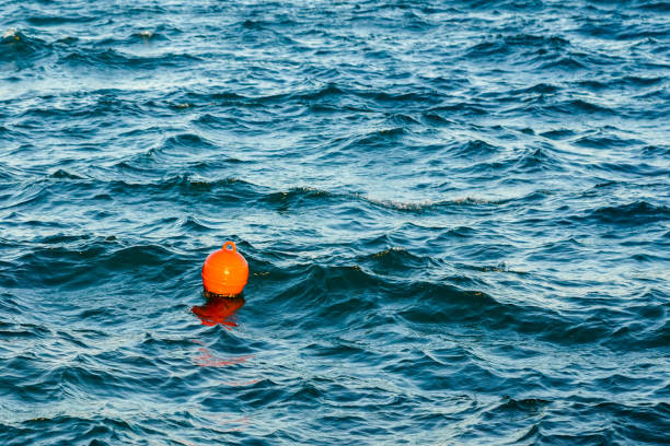 Orange plastic water buoy floating in turquoise sea water, wavy water background